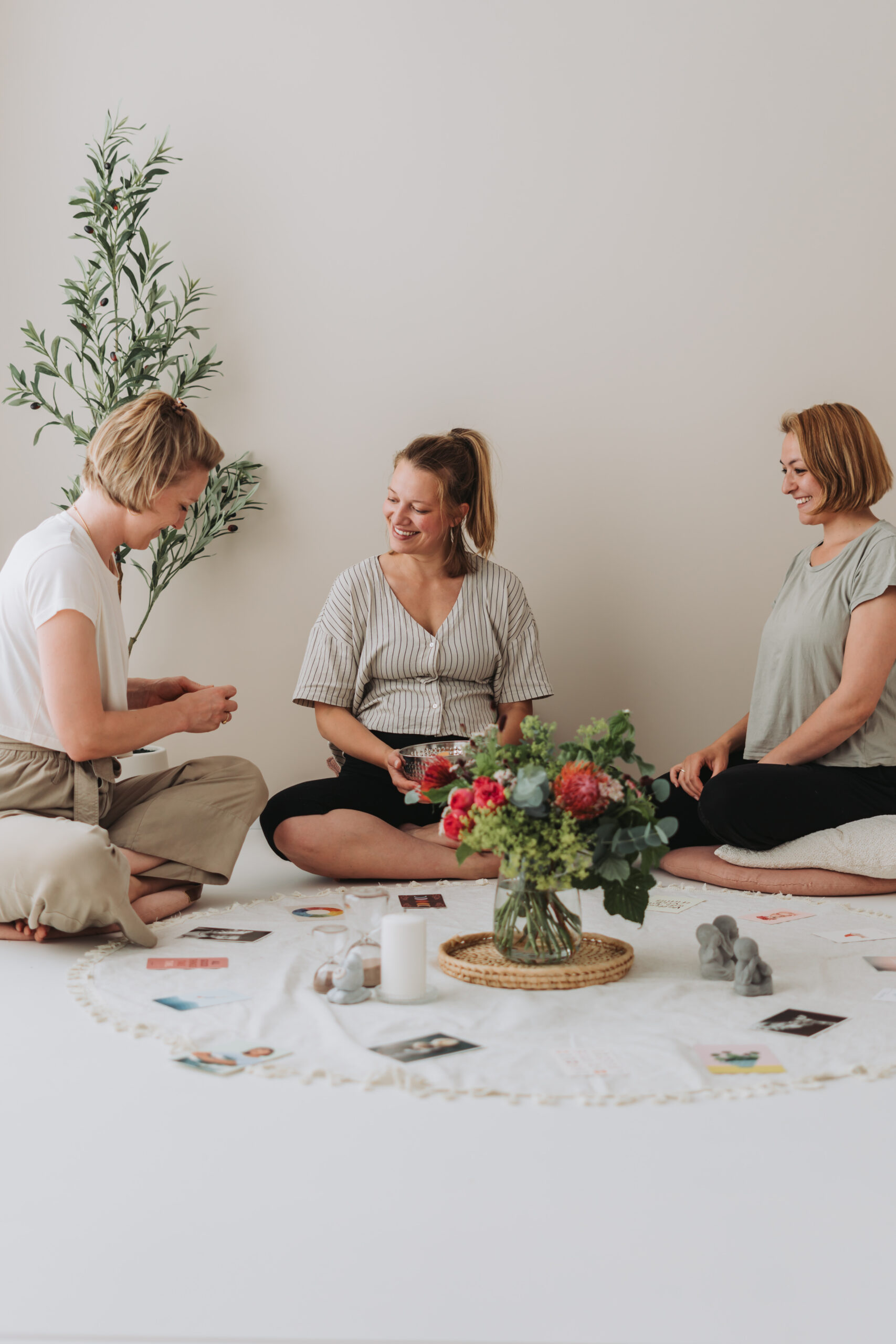 Drei Frauen sitzen im Kreis um Blumen und Kerzen bei einem Mama Blessing in Gauting