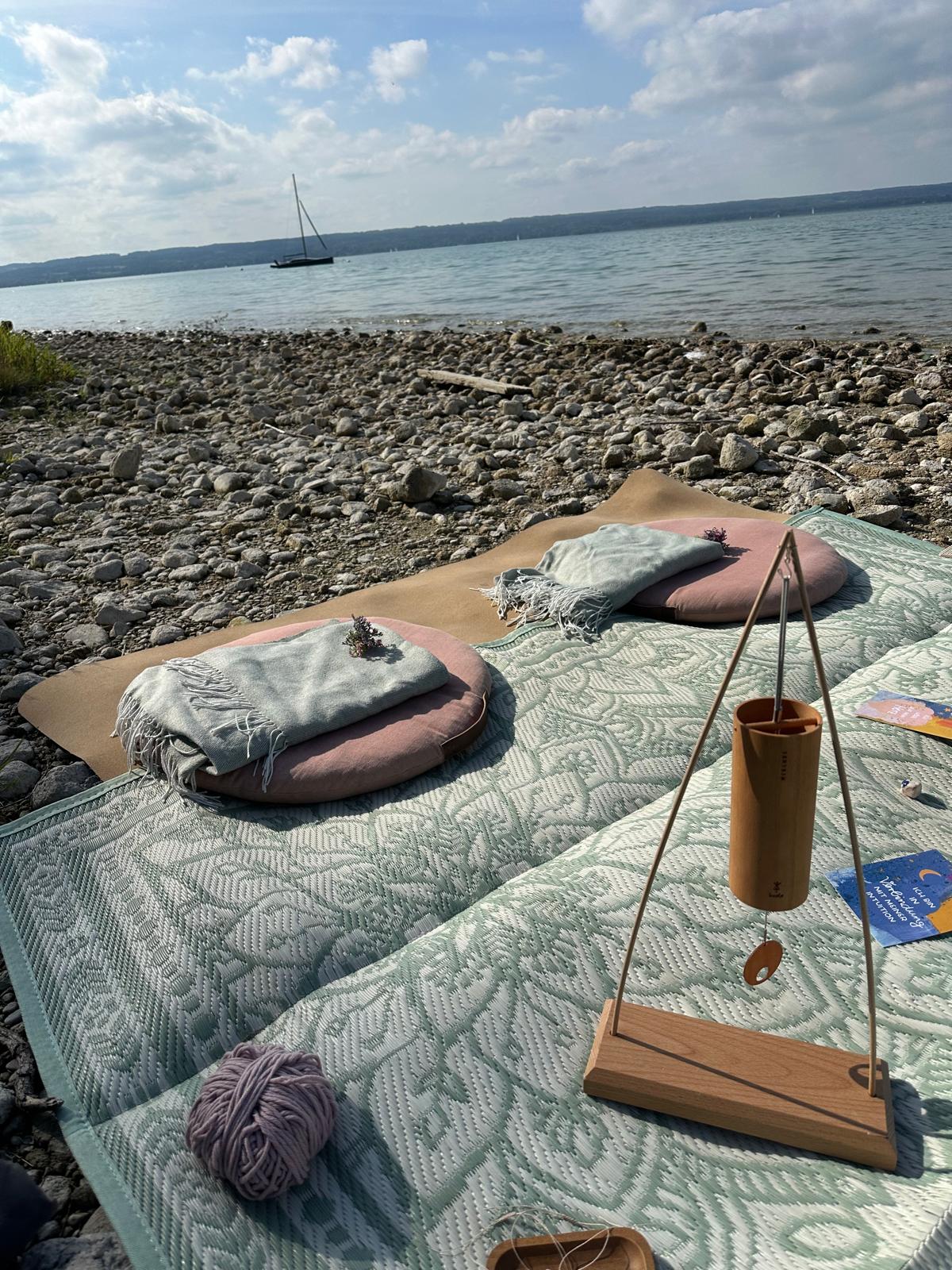 Aufbau für ein Mama Blessing am Seeufer mit Kissen, Decken und Klangspiel